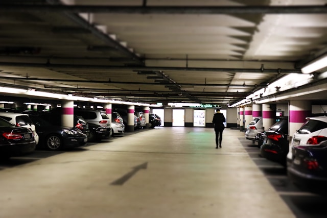 an underground car park full of parked cars with a person walking down the middle